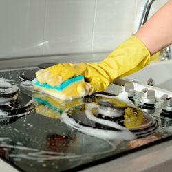 cleaner in yellow gloves scrubbing oven top